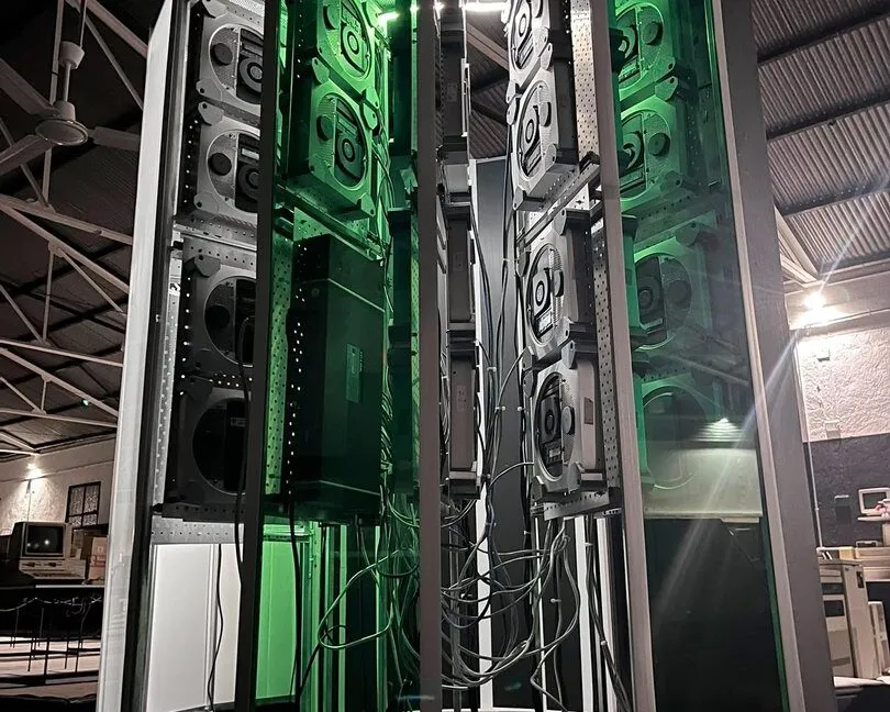 A vertical photo showing the size of the Cray-1 replica project. A large C-shaped tower stands lit up with green accent lighting.